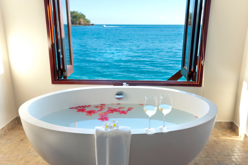 Wine glasses and rose petals in overwater bungalow bathtub